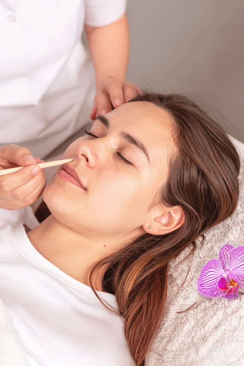 Réflexologie faciale Dien Cham réalisée avec un stylet en bois sur une jeune femme